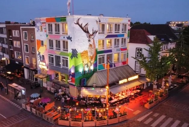 Gevel van Hotel Credible aan de Hertogstraat met streetart, in de avond